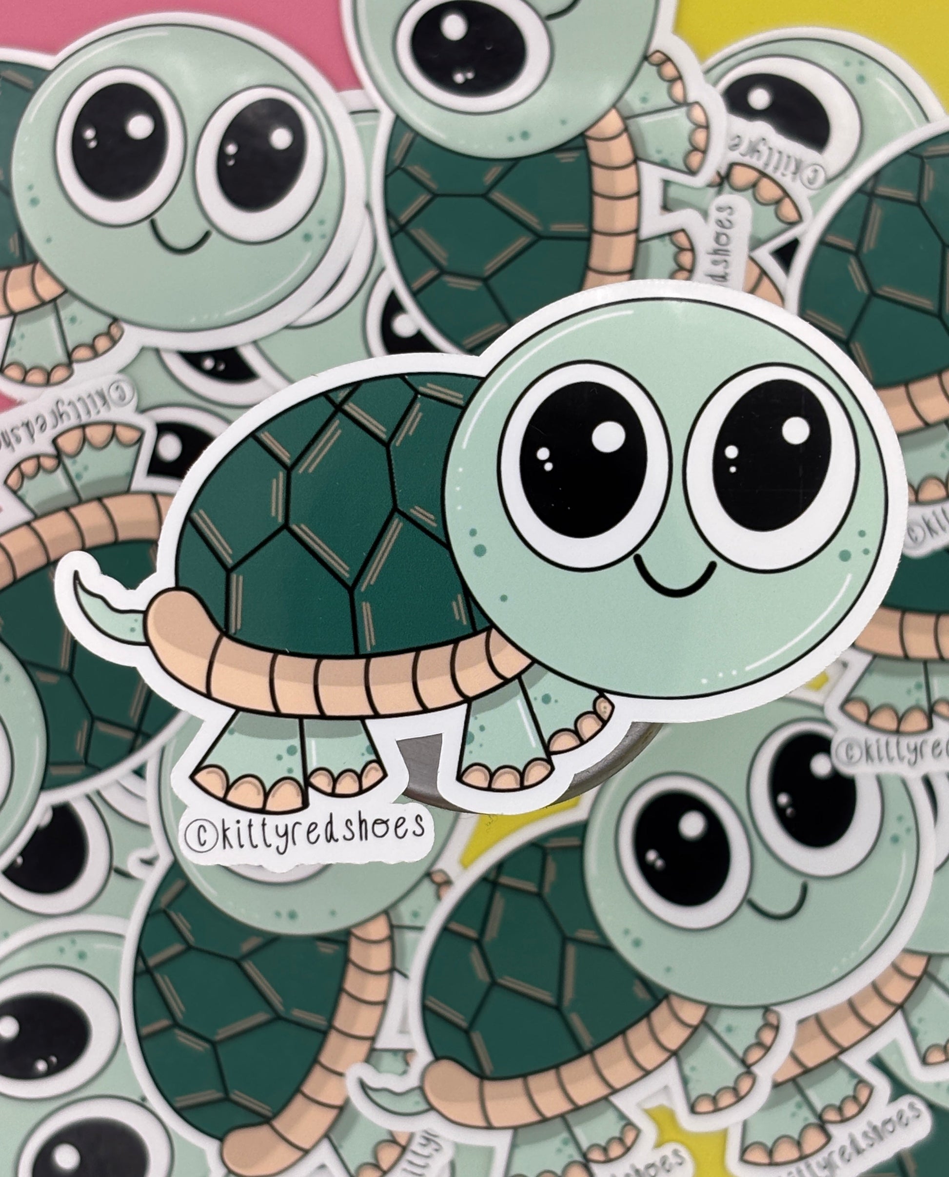 A cute green smiling turtle sticker with text copyright kittyredshoes resting on lots of the same sticker.